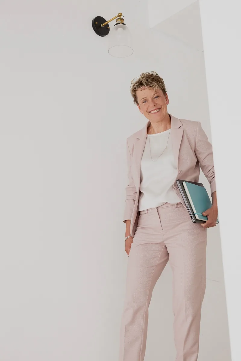 Britta Wein steht mit Laptop und Unterlagen auf der obersten Treppenstufe und blickt nach unten.