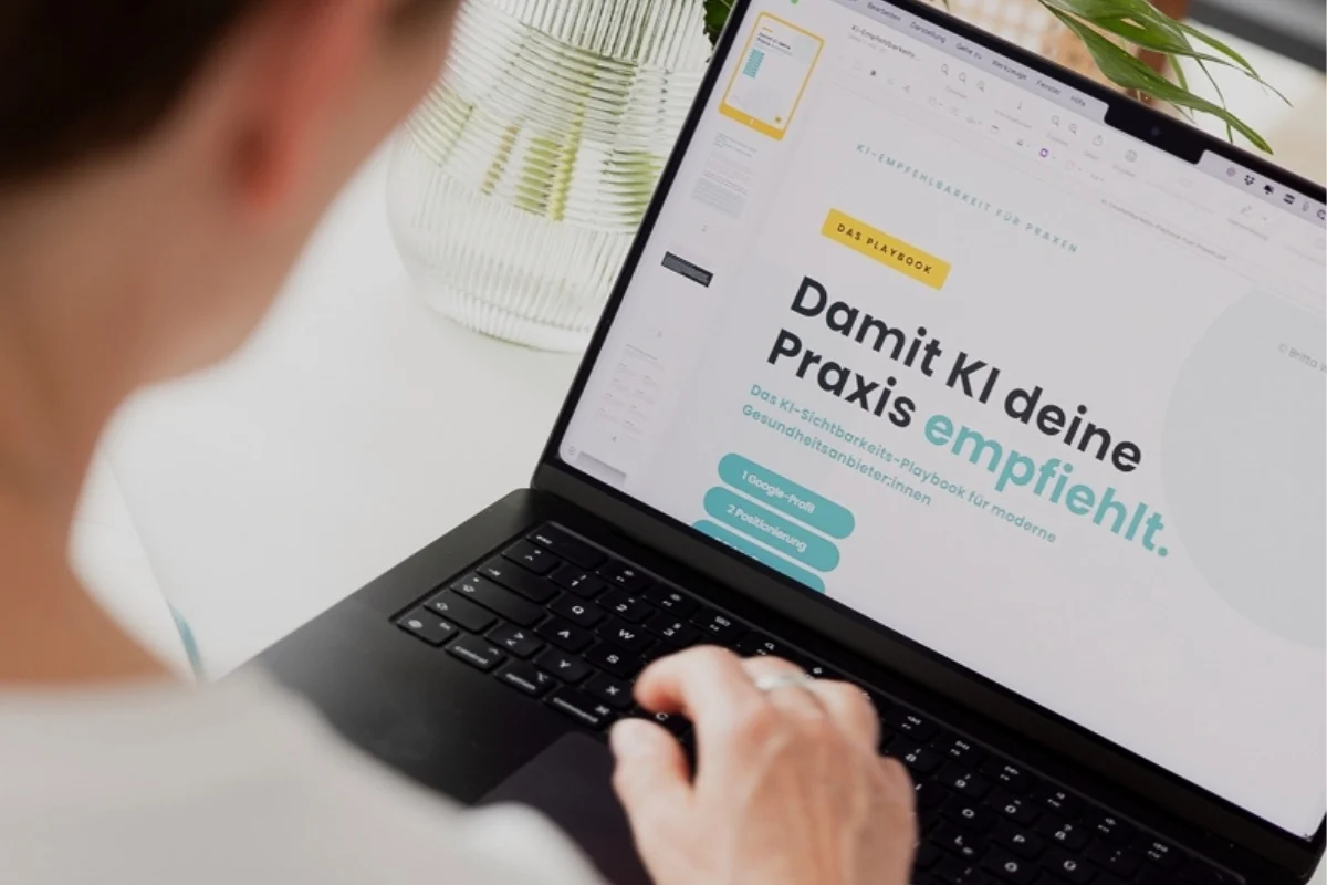 Britta Wein am Laptop mit dem KI-Sichtbarkeits-Playbook „Damit KI deine Praxis empfiehlt“